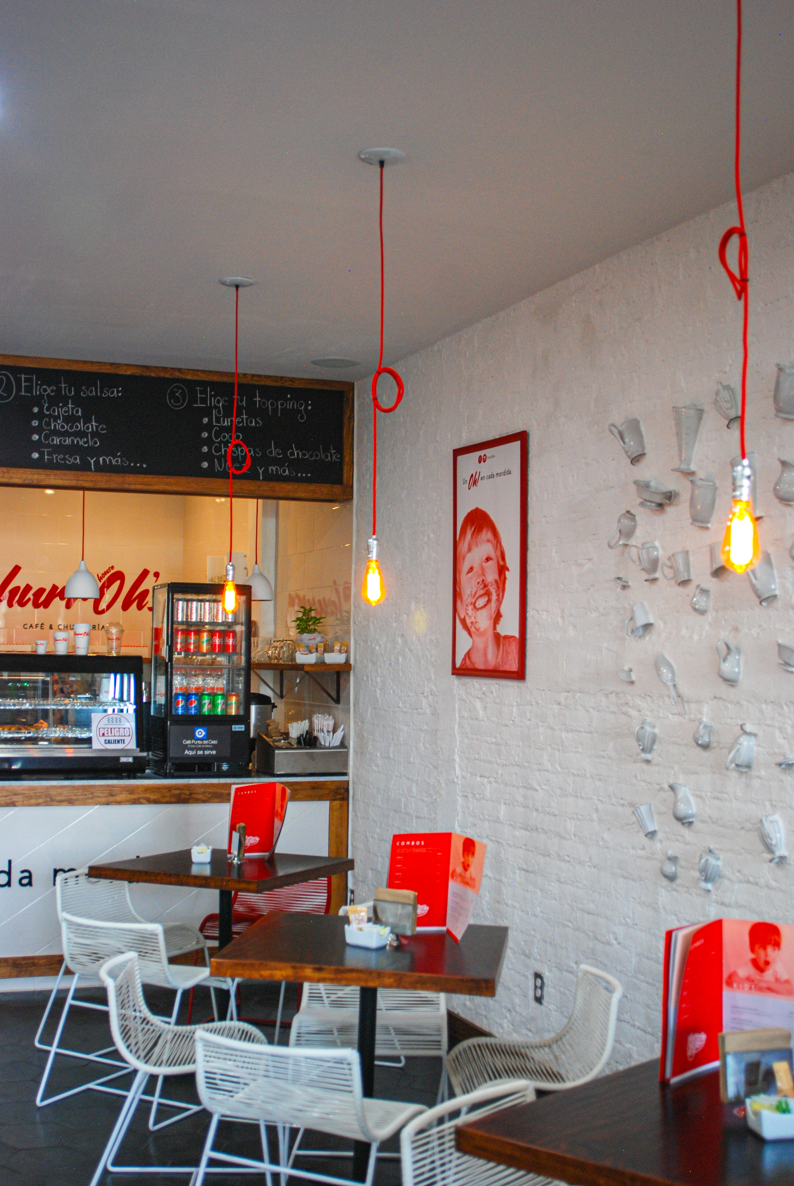 Área de preparación y mostrador de churrería con iluminación puntual, acabados interiores Fer Et Ciment